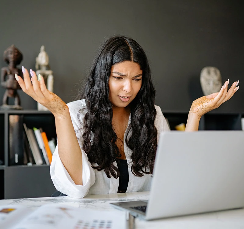 Young woman staring at computer, reading about SOC 2 certifications, confused by what they mean